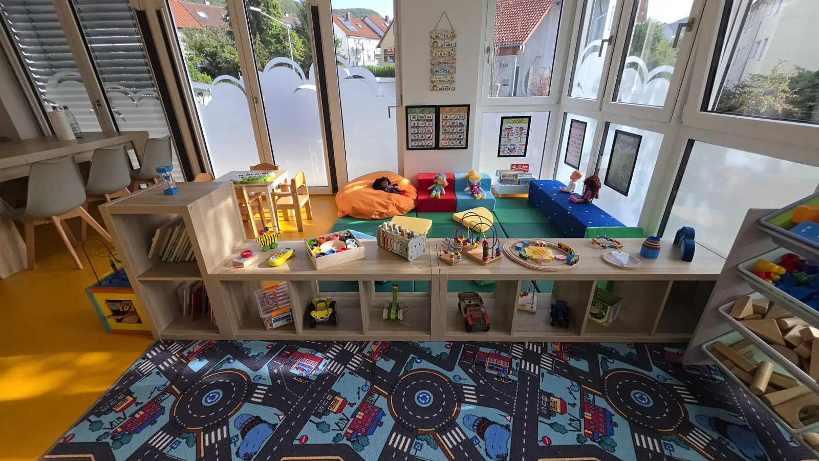 Heller Spielraum mit Spielteppich, Regalen voller Spielsachen und großen Fenstern